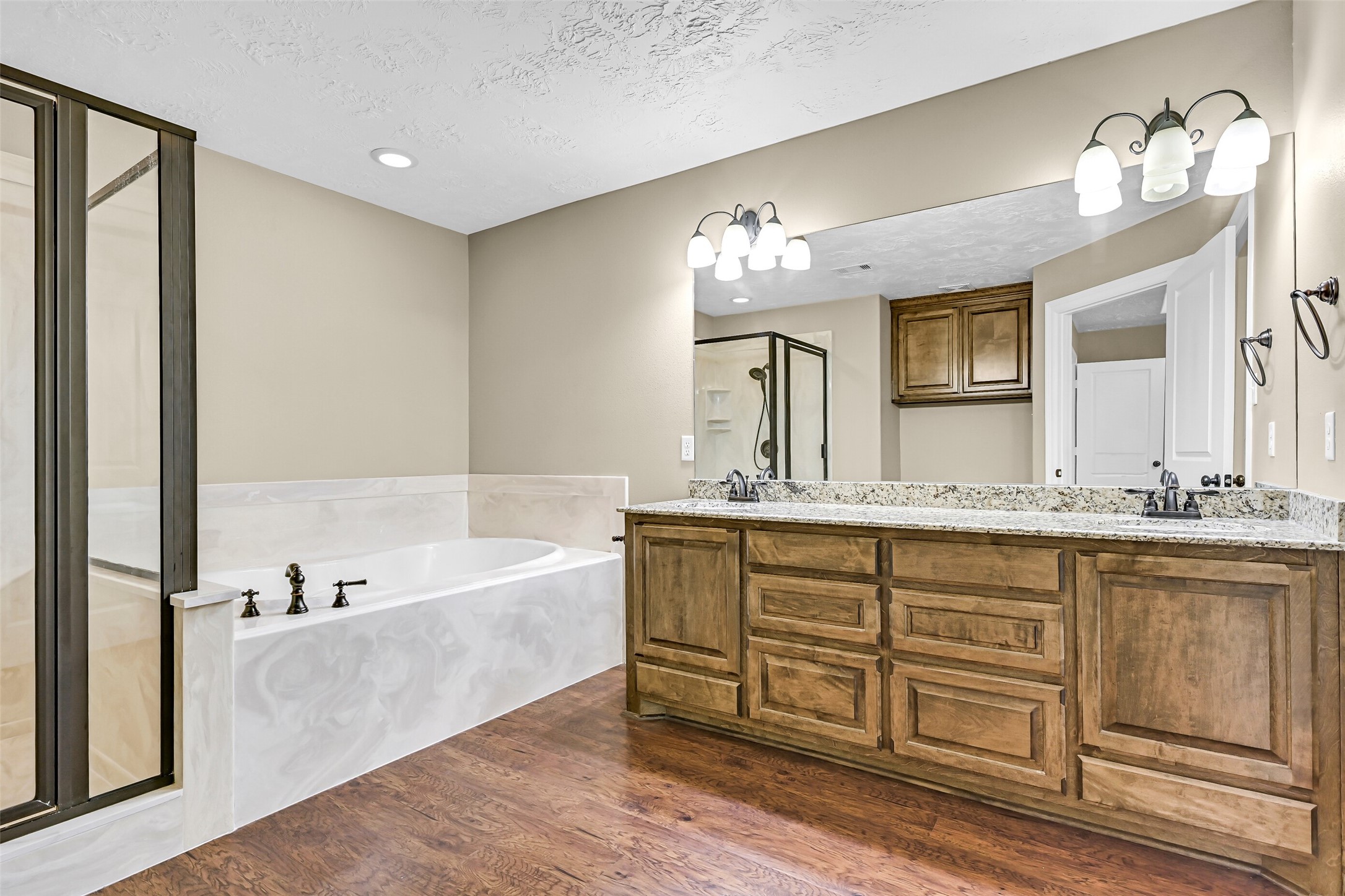 11930 Bastrop Beach Road Angleton, TX 77515 - Photo 21 of 29 The spacious ensuite bath showcases dual granite vanities with custom cabinetry, a relaxing soaking tub, separate shower, and plenty of room to begin and end each day in comfort.