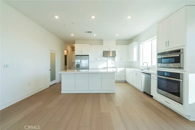 a large kitchen with stainless steel appliances granite countertop a stove a sink dishwasher and a oven with white cabinets