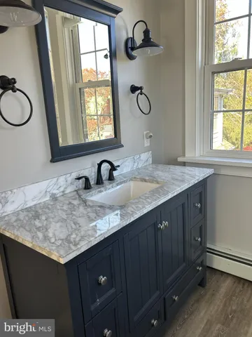 a bathroom with a granite countertop sink and a window