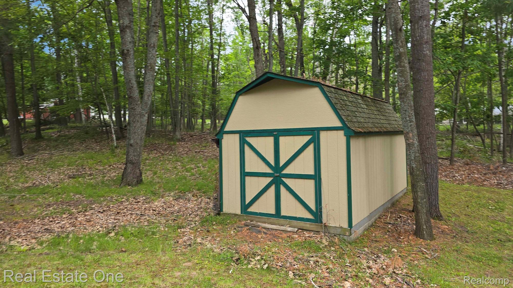 4233 Pheasant Road Lincoln, MI 48742 - Photo 5 of 19 Detached storage shed featuring a gambrel roof with shingle finish, light-toned siding, and dark green trim details
