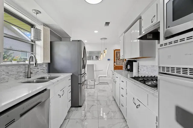 a kitchen with white cabinets and appliances