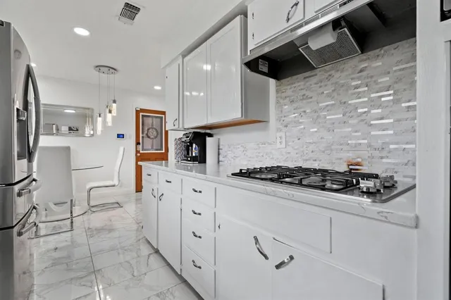 a kitchen with stainless steel appliances a stove a sink and white cabinets