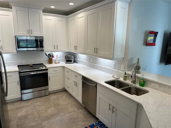 a kitchen with stainless steel appliances kitchen island granite countertop a refrigerator and a stove top oven