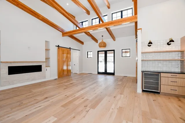 a view of an empty room with wooden floor and a fireplace