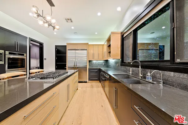 a large kitchen with stainless steel appliances a large counter top a stove and a sink