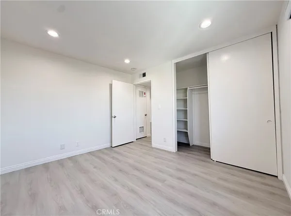 an empty room with wooden floor & windows and bathroom