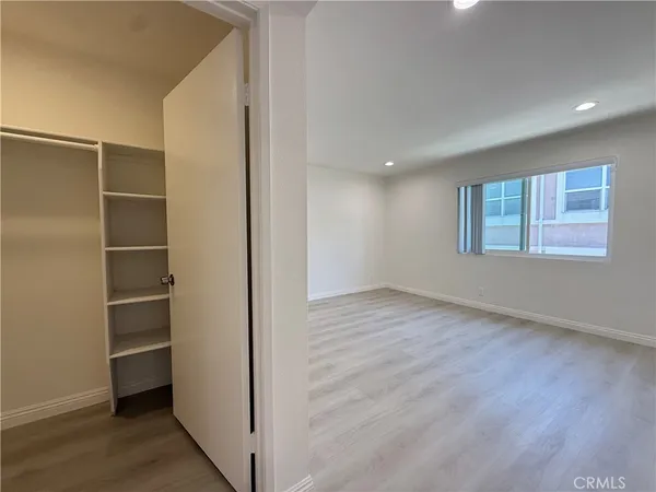 an empty room with wooden floor closet and windows