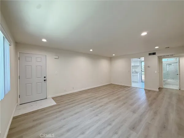 a view of an empty room with wooden floor and closet