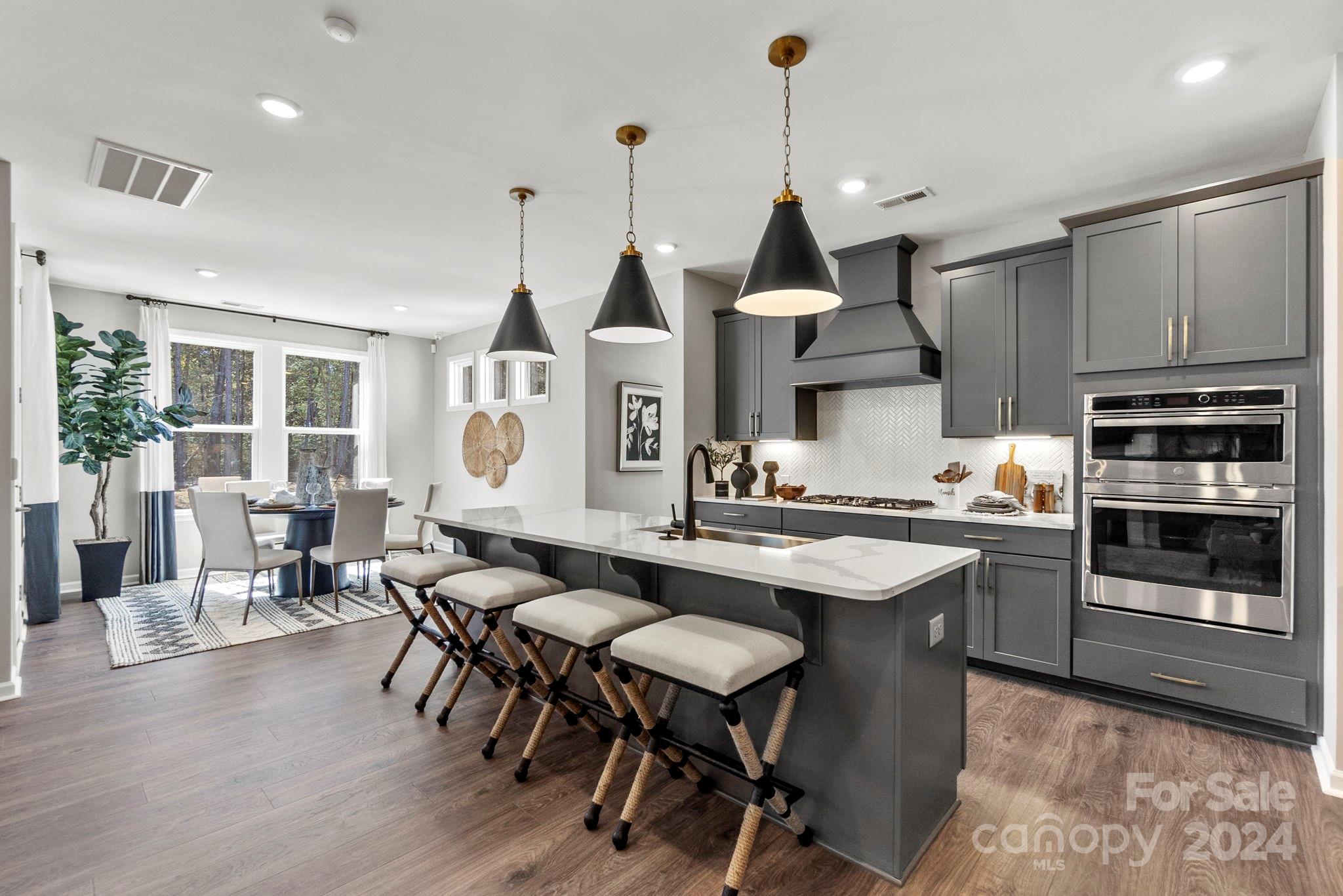 13229 Chopin Ridge Road Huntersville, NC 28078 - Photo 1 of 34 a kitchen with stainless steel appliances granite countertop a stove a kitchen island a dining table and chairs