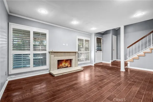 a view of an empty room with wooden floor fireplace and a window