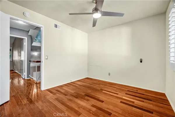 a view of empty room with wooden floor and fan