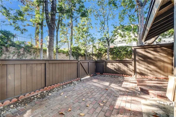 a view of backyard with wooden fence and large trees