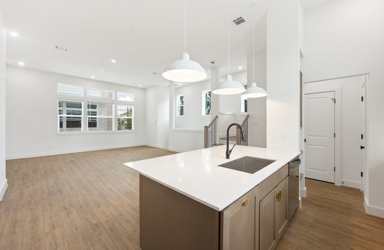 2121 Hoskins Drive, Unit C Houston, TX 77080 - Photo 20 of 34 A bright kitchen island overlooks the open living area, creating a seamless connection between cooking, dining, and gathering spaces. White quartz countertops, pendant lighting, black fixtures, warm cabinetry, and wide-plank flooring give the room a clean modern look with inviting warmth.