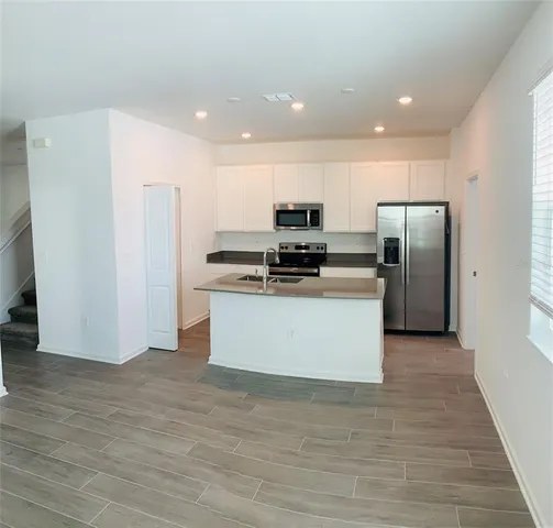 a large kitchen with stainless steel appliances a refrigerator and a stove top oven