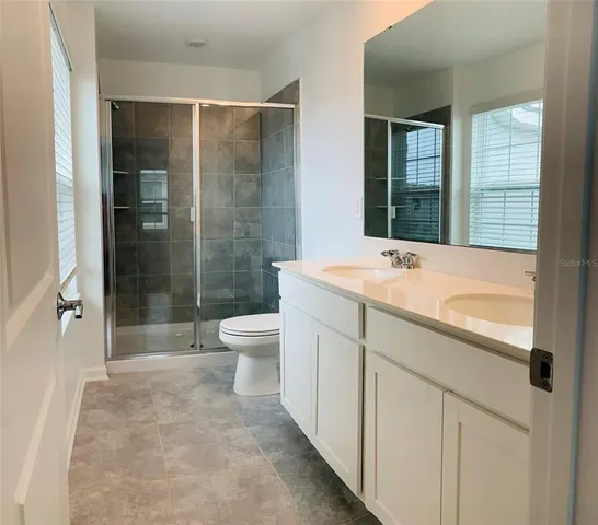 a bathroom with a shower sink vanity mirror and toilet