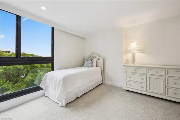 a spacious bedroom with a bed lamp and window