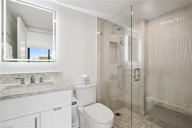 a bathroom with a granite countertop sink toilet a mirror a shower and a vanity