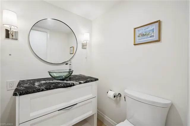 a bathroom with a granite countertop toilet and a mirror