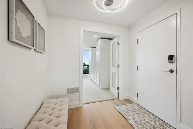 a view of a hallway with wooden floor and cabinet