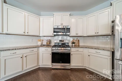 a kitchen with granite countertop white cabinets and stainless steel appliances