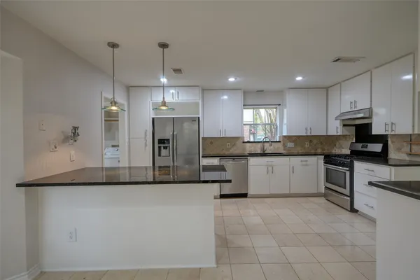 a large kitchen with granite countertop a large counter top stainless steel appliances and cabinets