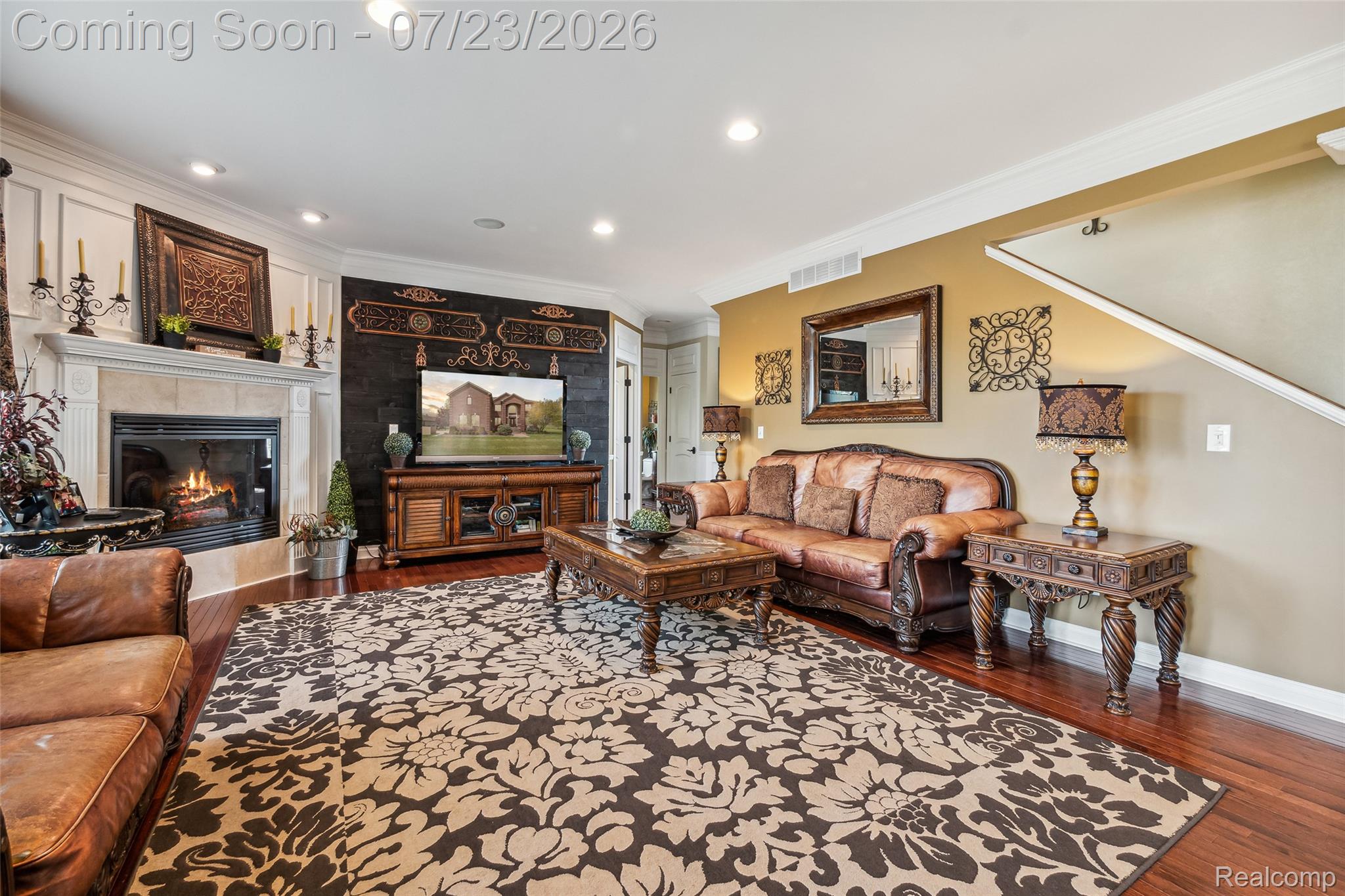 5460 Cochrane Road Almont, MI 48003 - Photo 6 of 48 Living area featuring a stone mantel fireplace, paneled accent wall, dark wood-finish flooring, recessed lighting, and a partial staircase
