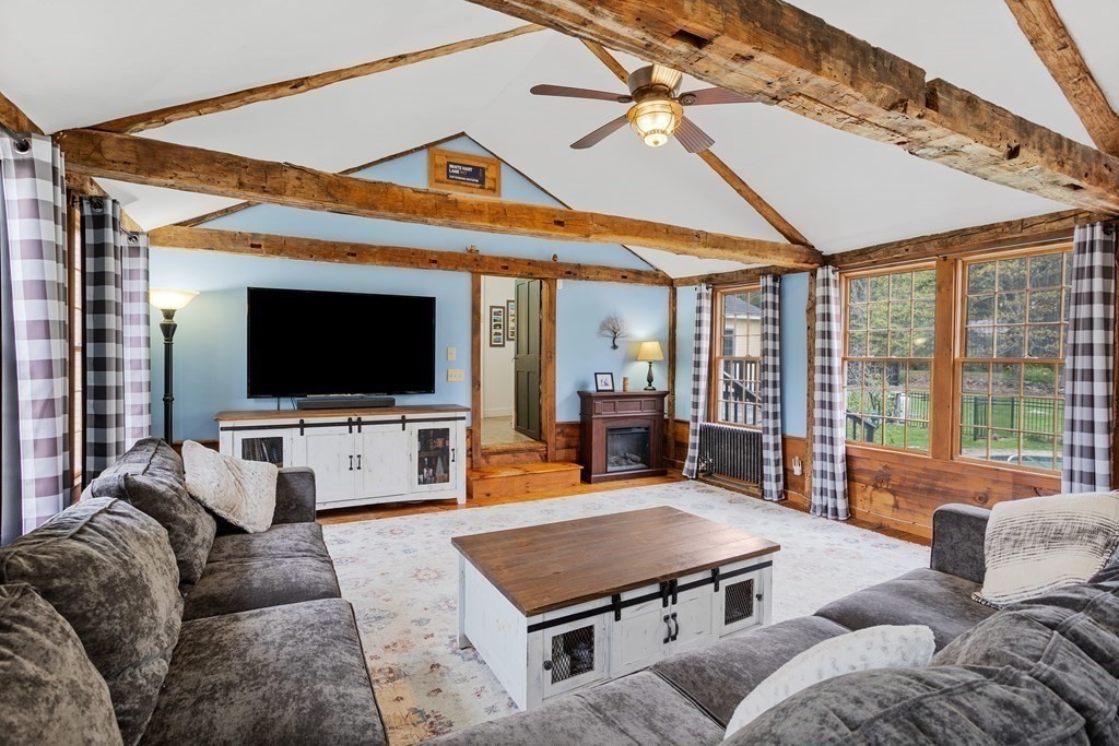 85 Forest Street Dunstable, MA 01827 - Photo 14 of 42 a living room with furniture a flat screen tv and a floor to ceiling window