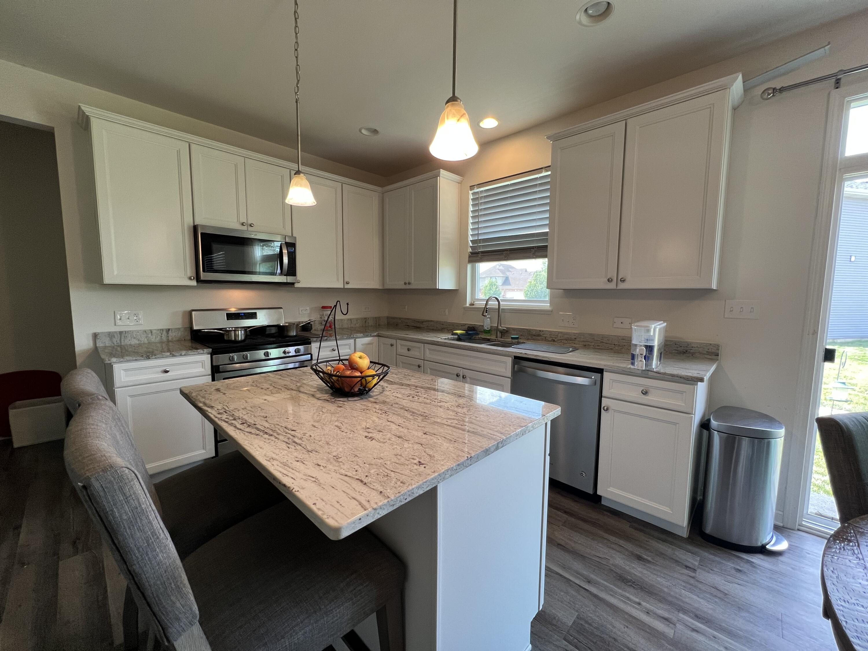 10193 California Street Crown Point, IN 46307 - Photo 3 of 33 a kitchen with a stove a sink a microwave a dining table and chairs