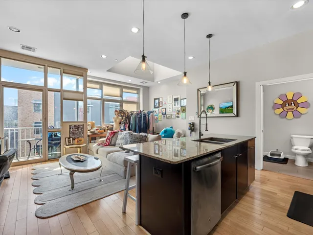 a living room with stainless steel appliances kitchen island granite countertop a large window and a counter space