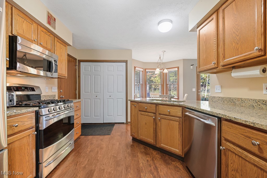 3982 Baird Road Stow, OH 44224 - Photo 11 of 50 Kitchen with stainless steel appliances, dark wood-type flooring, brown cabinetry, and a textured ceiling