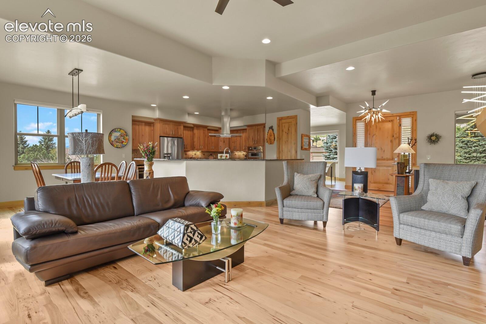 Open-concept living area with wood-finish flooring, recessed lighting, and a ceiling fan