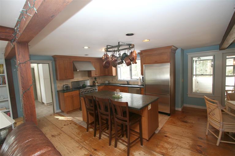 272 Pine Ridge Road Cotuit, MA 02635 - Photo 8 of 19 a kitchen with stainless steel appliances kitchen island granite countertop a refrigerator a stove a microwave oven a dining table and chairs with wooden floor
