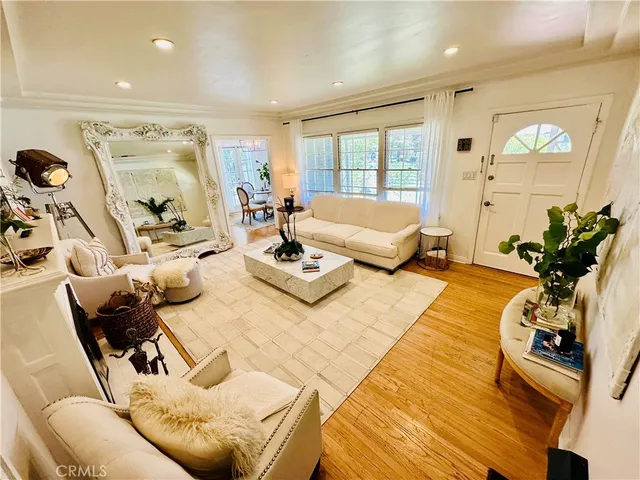 a living room with furniture hard wood floor and a floor to ceiling window