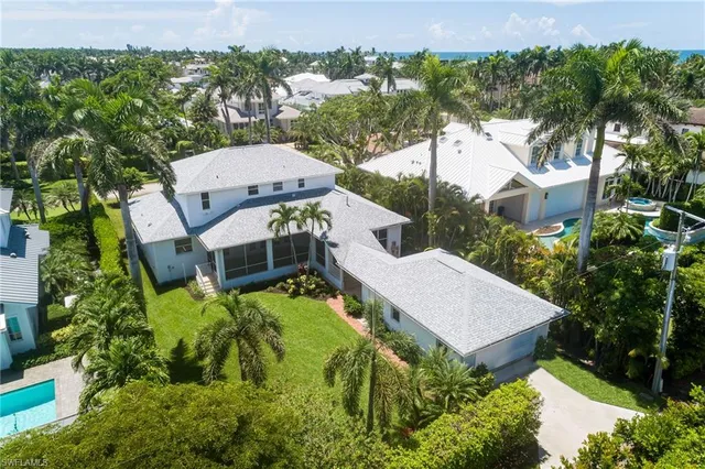 an aerial view of a house with swimming pool and large trees