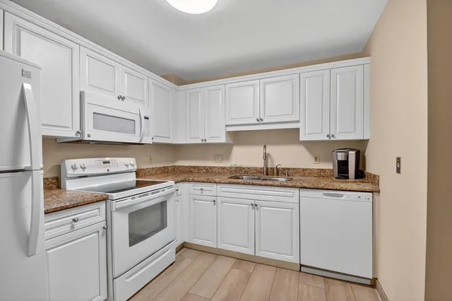 a kitchen with granite countertop white cabinets and white appliances