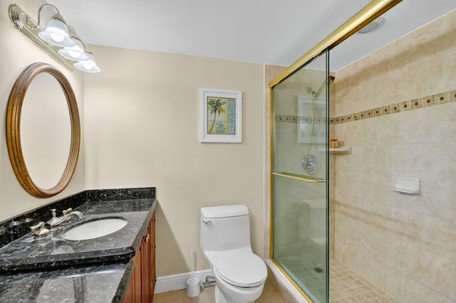 a bathroom with a granite countertop sink mirror vanity and toilet