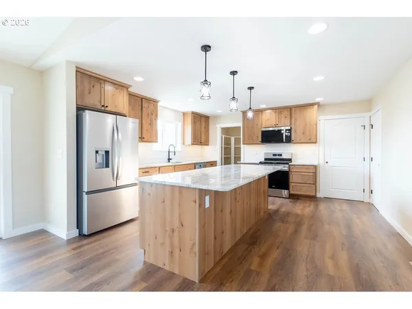 a kitchen with stainless steel appliances granite countertop a refrigerator a stove top oven a sink dishwasher and a refrigerator with wooden floor