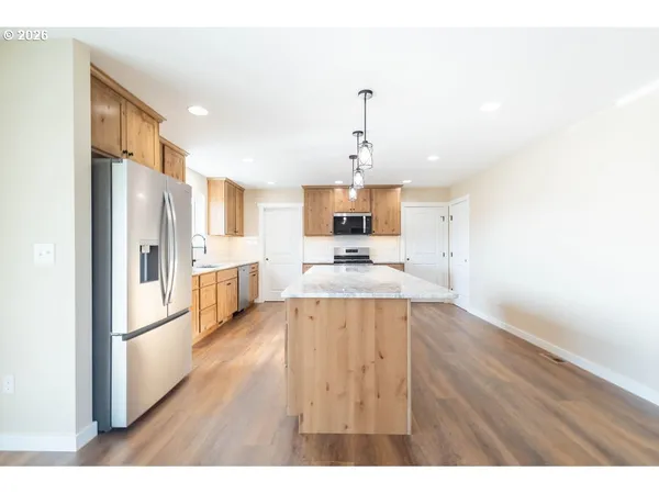 a view of a kitchen with a sink refrigerator and wooden floor