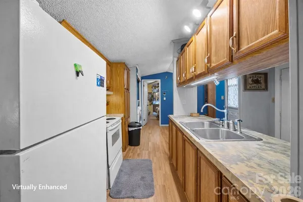 a kitchen with stainless steel appliances granite countertop a refrigerator a stove and a sink with wooden floor