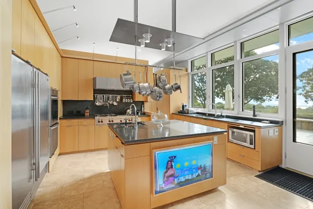 a kitchen with stainless steel appliances granite countertop a stove a refrigerator and a flat screen tv