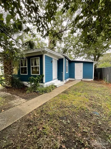 a front view of house with yard and trees around