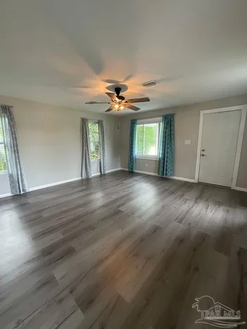 an empty room with wooden floor and windows