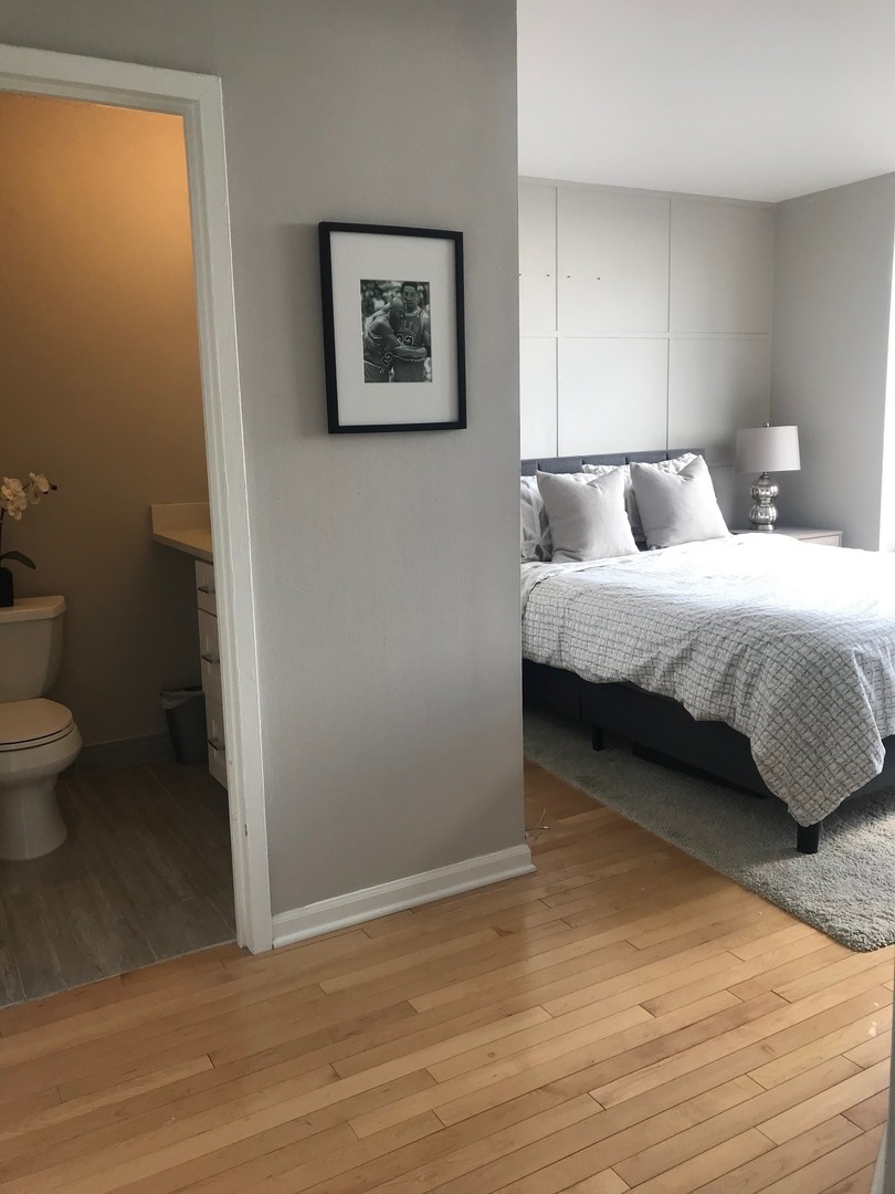 3930 North Pine Grove Avenue, Unit 1606 Chicago, IL 60613 - Photo 11 of 17 a spacious bedroom with a bed and a wall painting