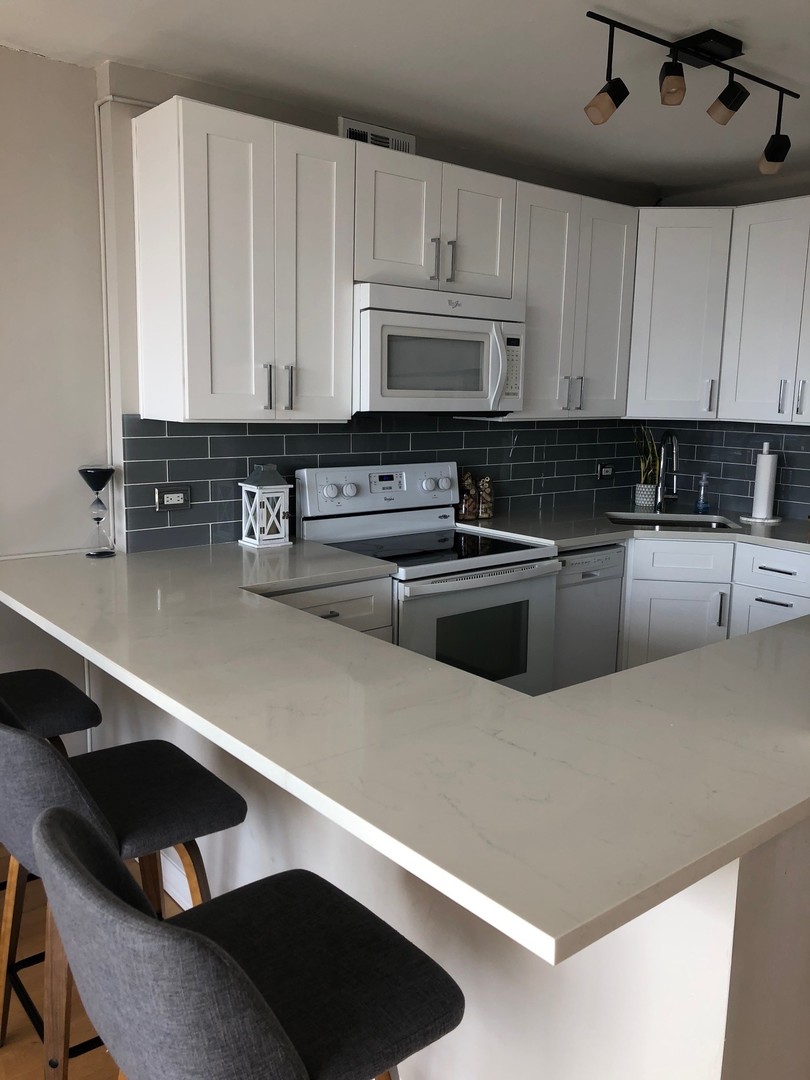 3930 North Pine Grove Avenue, Unit 1606 Chicago, IL 60613 - Photo 6 of 17 a kitchen with granite countertop a sink a stove and cabinets