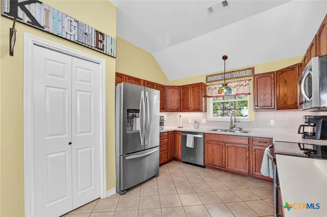 a kitchen with stainless steel appliances granite countertop a refrigerator and a stove top oven