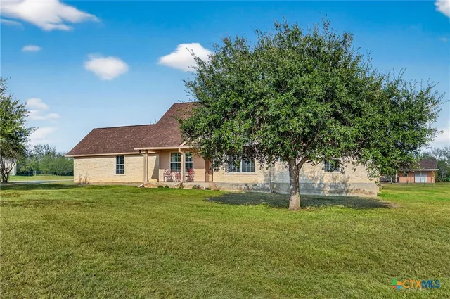 a front view of a house with yard and tree