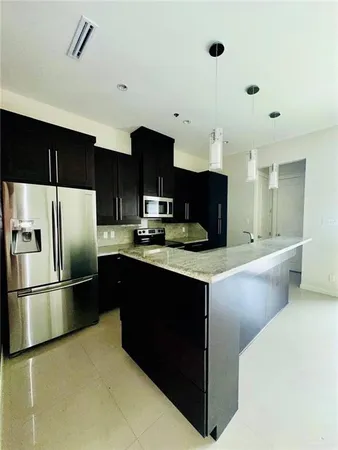 a kitchen with stainless steel appliances kitchen island granite countertop a refrigerator and a sink