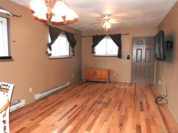 a view of empty room with wooden floor and fan