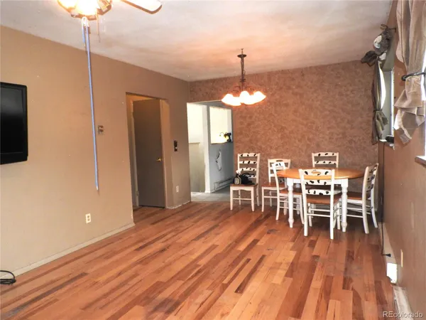 a dining room with wooden floor a chandelier a wooden table and chairs