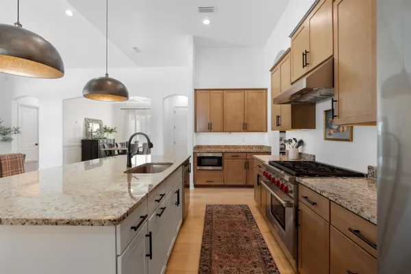 a kitchen with granite countertop a sink a stove and a wooden floor